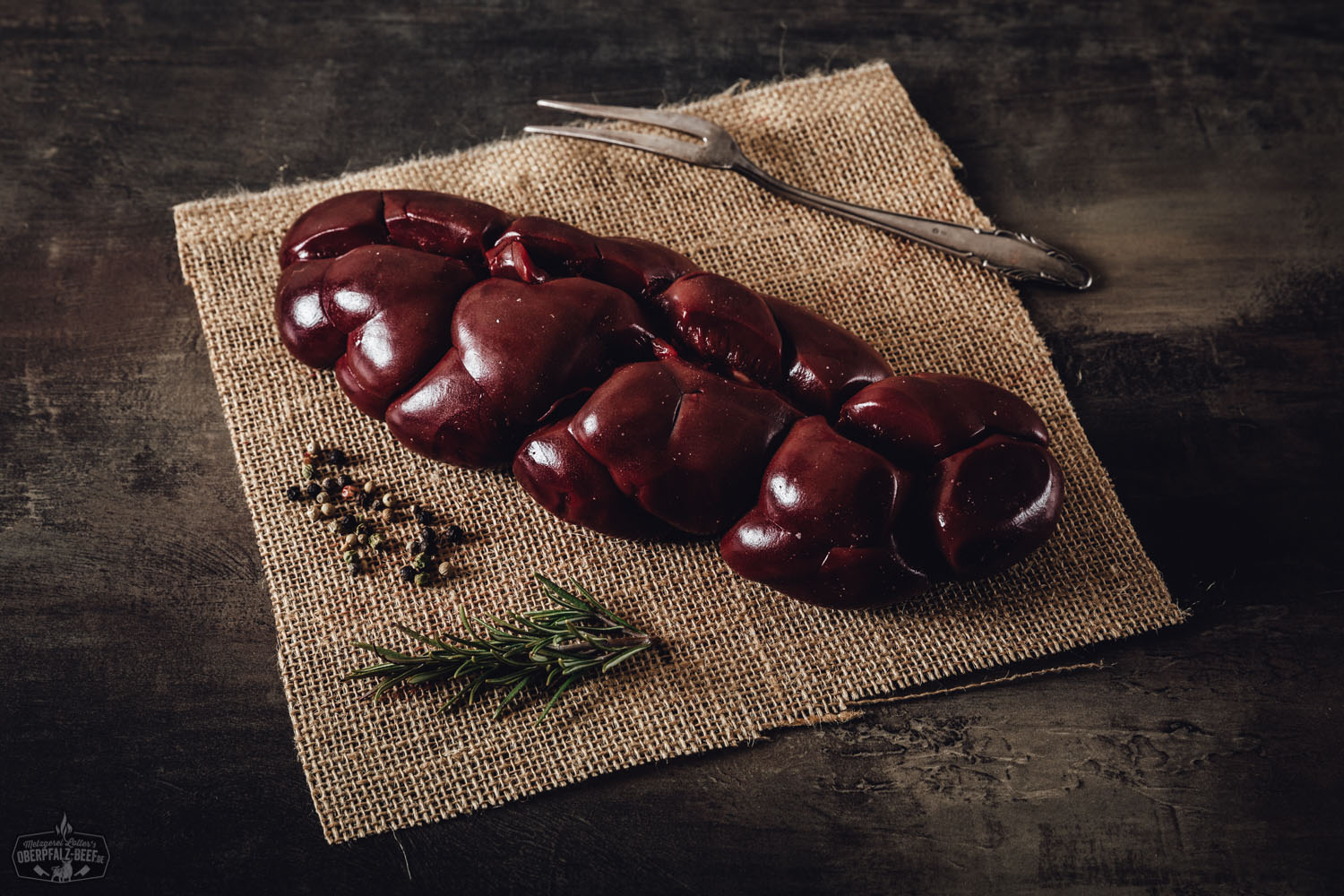 Bild zeigt eine rohe Schweineniere auf einem Holztisch, frisch und bereit zur Zubereitung. Perfektes Beispiel für hochwertiges Fleisch von Oberpfalz Beef. Ideal für Rezepte mit Innereien.