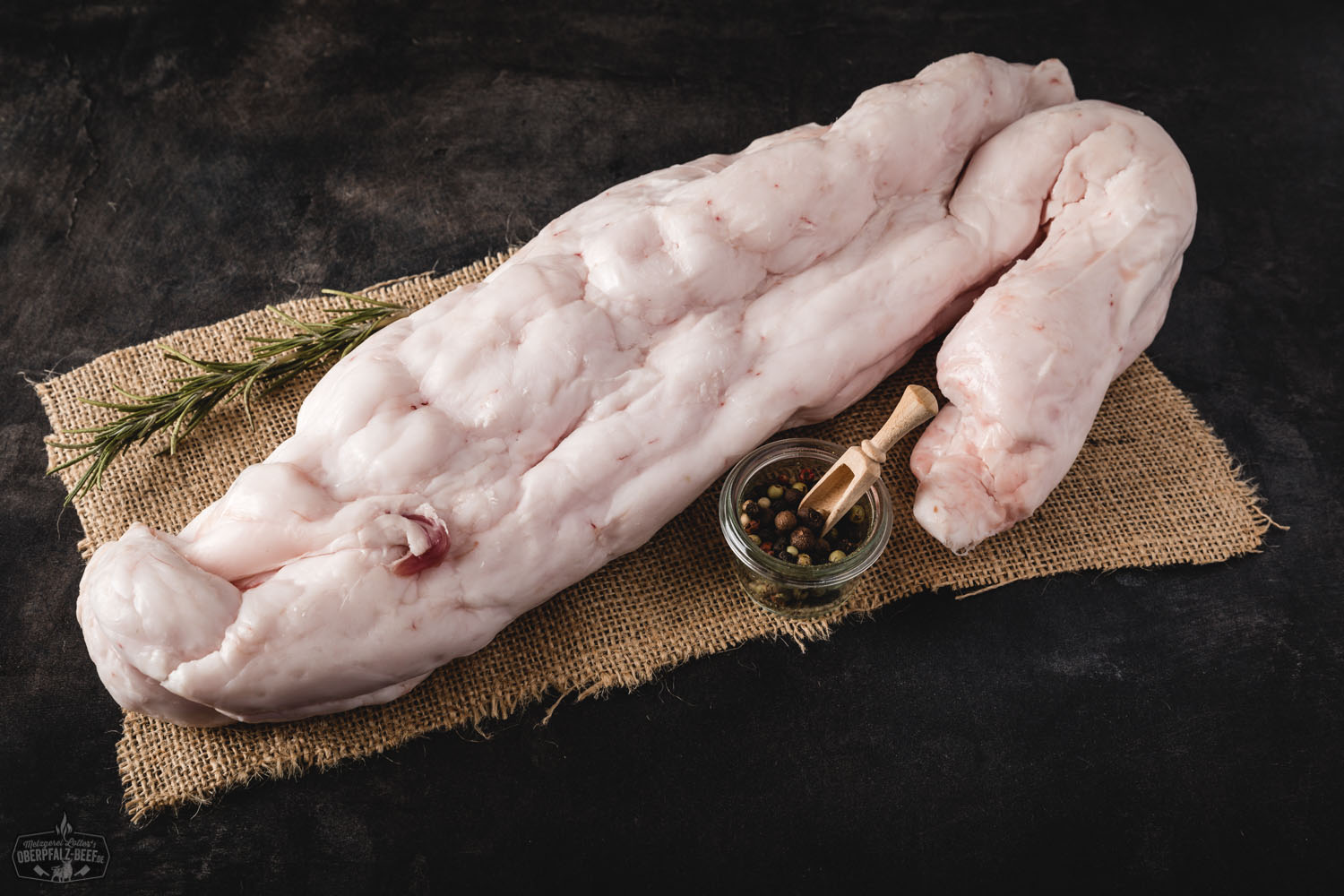 Frisch geschnittener Schmeer (Talg) vom Oberpfälzer Landschwein, roh und naturbelassen auf einem dunklen Brett angerichtet, umgeben von grobem Meersalz, Kräutern und Gewürzen – hochwertiger Schweineschmalz für traditionelle bayerische Küche.