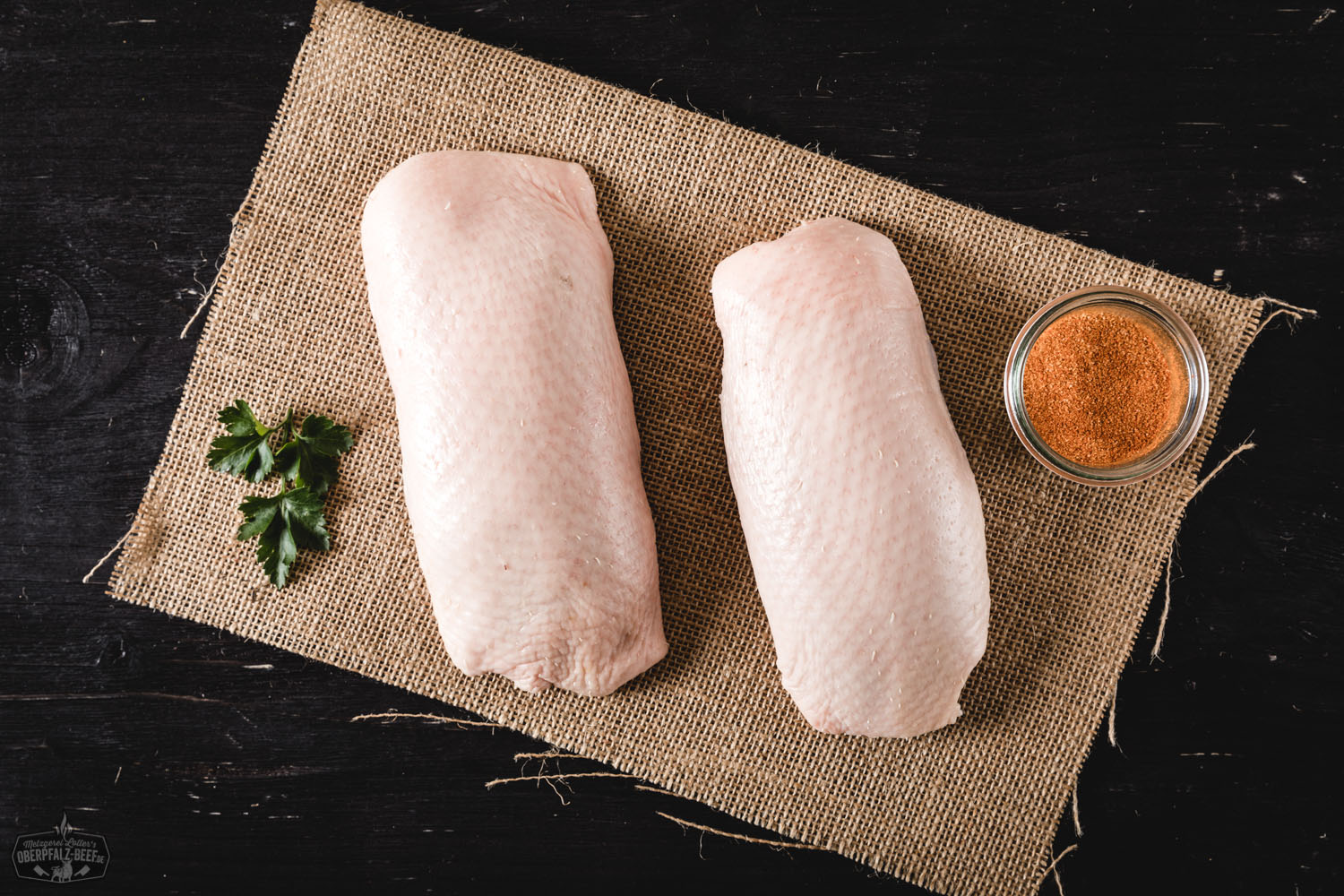 Rohes Brustfilet von der Oberpfälzer Bauernente, auf dunklem Untergrund angerichtet, umgeben von frischen Kräutern, grobem Salz und Gewürzen – hochwertige Entenbrust aus regionaler Landwirtschaft für bewusste Genießer.