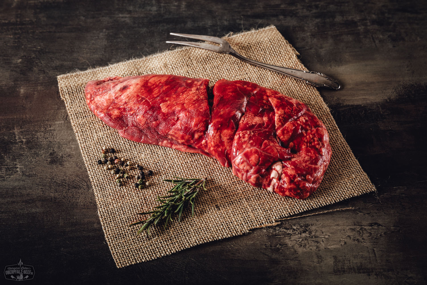 Rohe Kalbslunge vom Oberpfälzer Kalb auf schwarzer Schieferplatte, in mundgerechte Stücke geschnitten, rosarote Farbe mit zarter Marmorierung, hochwertige Innerei als Delikatesse, ideal für traditionelle Rezepte in der regionalen bayerischen Küche.