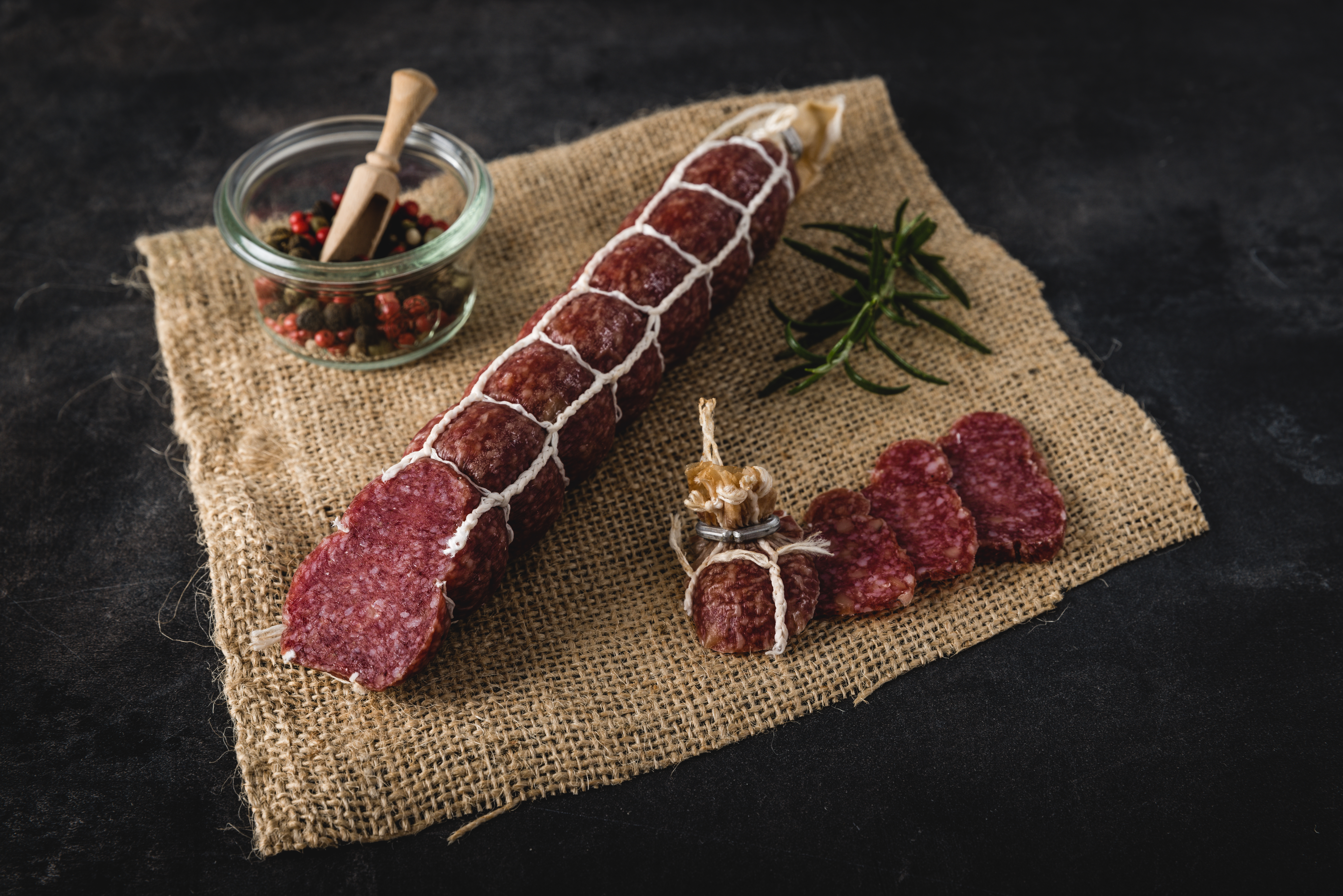 Mandel-Amaretto-Salami auf rustikalem Holzbrett mit Nüssen und Amarettokeksen, ideal für Feinschmecker und Genießer.