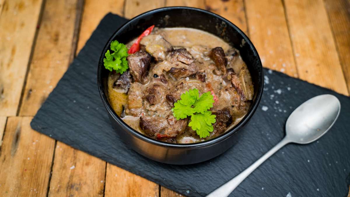 Handgeschnittenes Gulasch vom Oberpfalz-Rind – Frisch & Regional Rinderbraten aus der falschen Lende vom Oberpfalz-Rind, roh und mariniert, auf schwarzem Untergrund angerichtet, mit frischen Kräutern und Gewürzen garniert – hochwertiges deutsches Rindfleisch ideal zum Schmoren oder Braten.