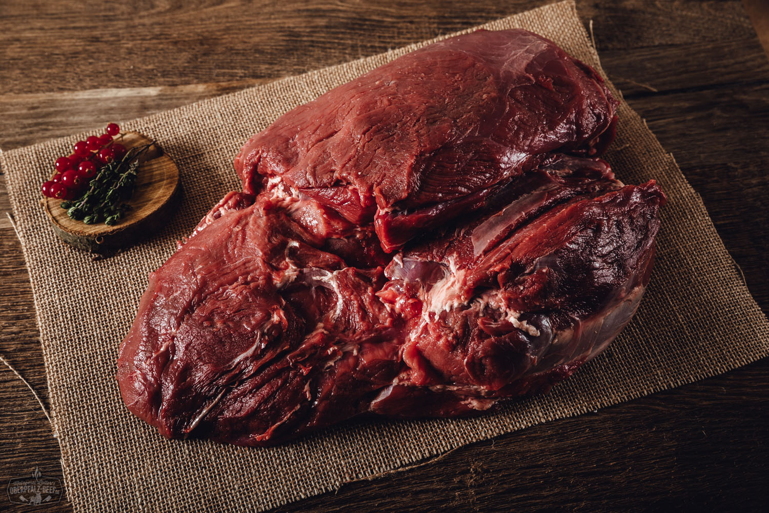 Wildschwein Keule ohne Knochen aus der Oberpfalz – Regionales Fleisch in Premiumqualität Rohe Keule ohne Knochen vom Oberpfälzer Wildschwein auf schwarzem Untergrund, von frischen Rosmarinzweigen, Pfefferkörnern und Meersalz umgeben – hochwertiges Wildfleisch aus nachhaltiger Jagd, ideal für Braten oder Schmoren.