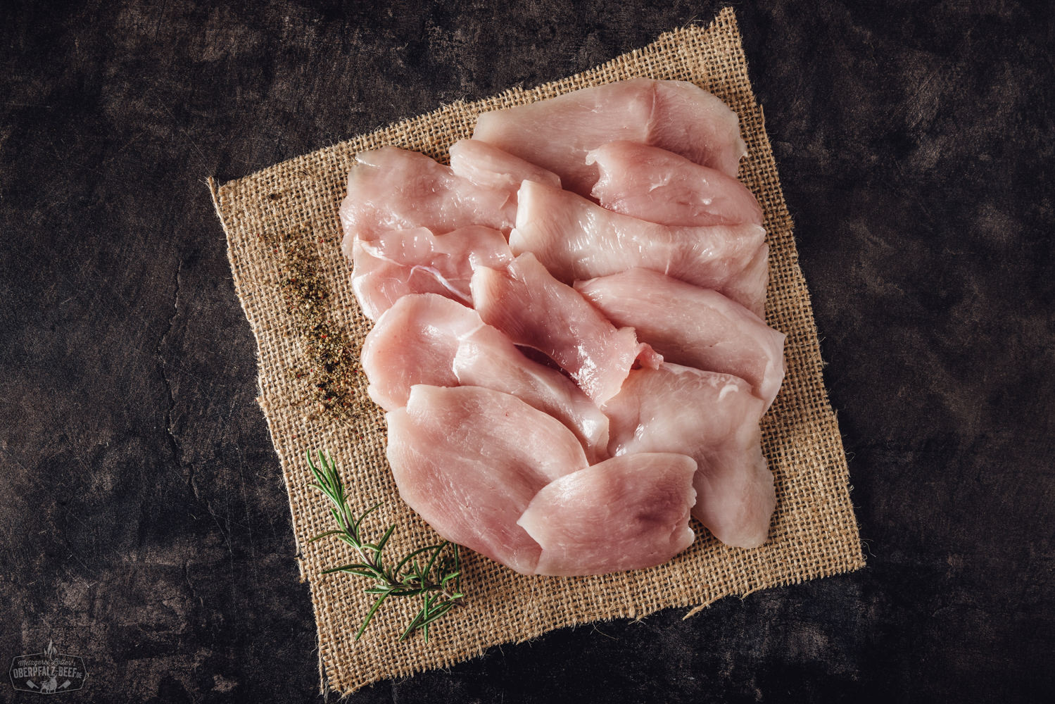 Handgeschnittene Hähnchenbrust für Raclette – zartes Geflügelfleisch in Premiumqualität Handgeschnittene Hähnchenbruststreifen auf einem rustikalen Holzbrett, angerichtet für Raclette, mit frischen Kräutern garniert – zartes, hochwertiges Geflügelfleisch ideal für Raclette-Grill oder Pfännchen.