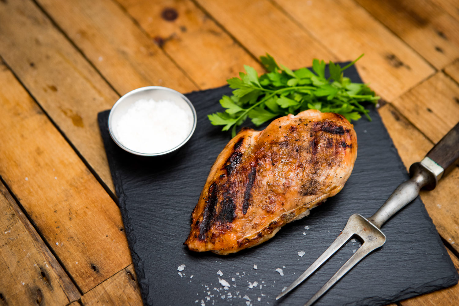 Brustfilet vom Oberpfälzer Bauernhähnchen – Frisches Hähnchenfleisch regionaler Herkunft Rohes Brustfilet vom Oberpfälzer Bauernhähnchen auf dunkler Unterlage, angerichtet mit frischem Rosmarin, Knoblauchzehen, schwarzen Pfefferkörnern und Meersalz – hochwertiges, regionales Hähnchenfleisch für gesundes Kochen.