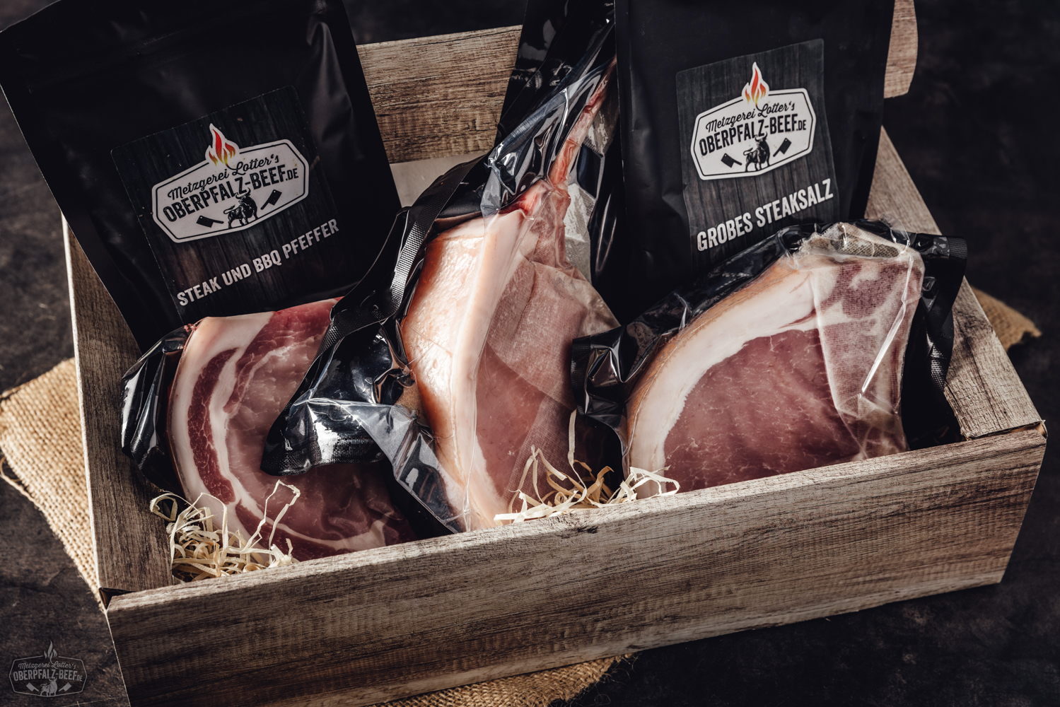 Hausgemachte Schweinshaxe frisch vom Grill – Oberpfälzer Spezialität genießen Zwei Frauen in ländlicher Umgebung halten jeweils ein Ferkel auf dem Arm und lächeln in die Kamera; im Hintergrund ist ein moderner Stall mit der Aufschrift „Oberpfalz Beef“ zu sehen – authentische Schweinehaltung auf einem Bauernhof in Bayern.