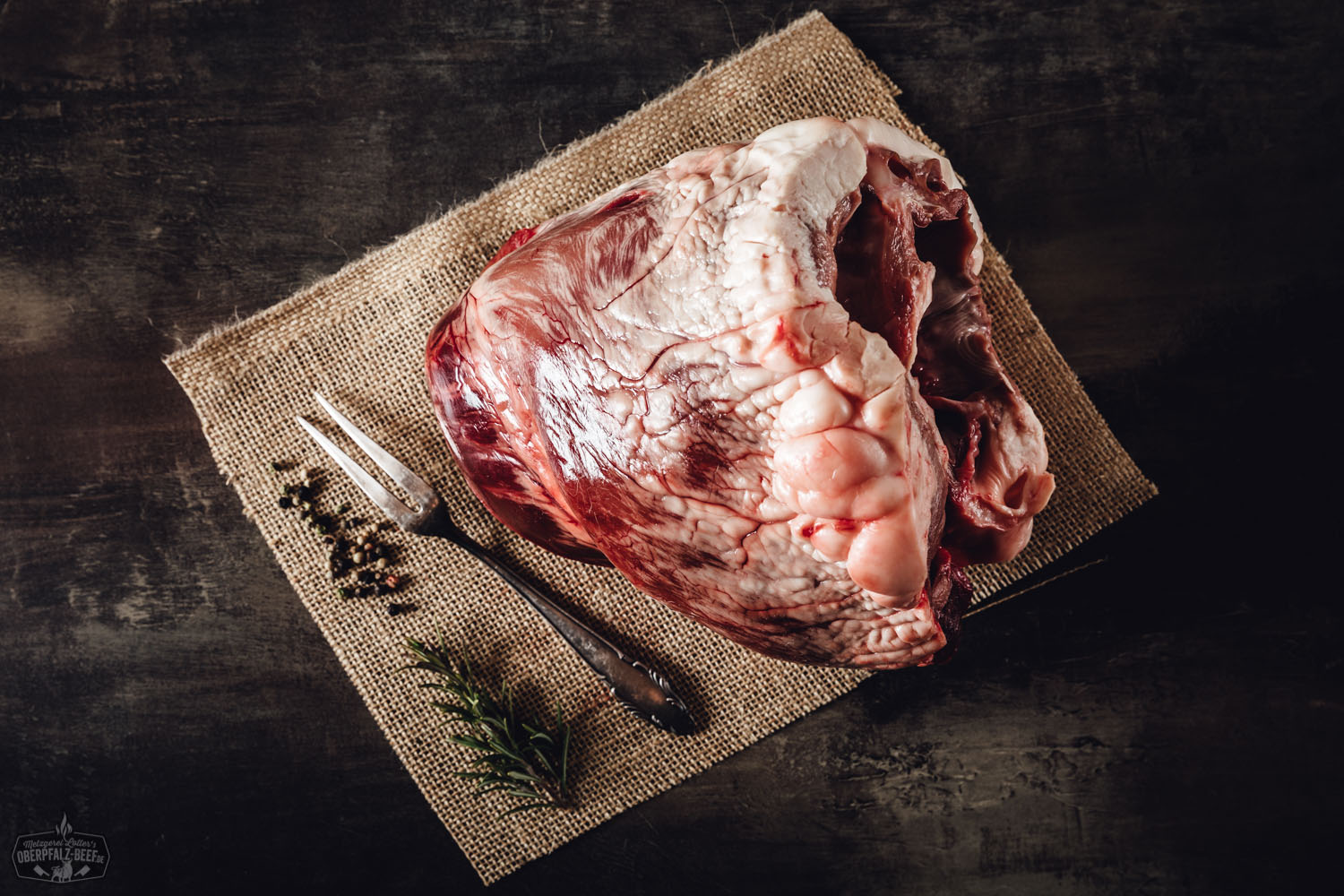 Herz vom Oberpfälzer Milchkalb – Regionales Kalbfleisch in Premiumqualität Rohes Kalbsherz vom Oberpfälzer Milchkalb, aufgeschnitten und auf einem dunklen Schneidebrett angerichtet, mit sichtbarer Fleischstruktur und feiner Marmorierung – frisch, hochwertig und ideal für bewusste Fleischliebhaber.