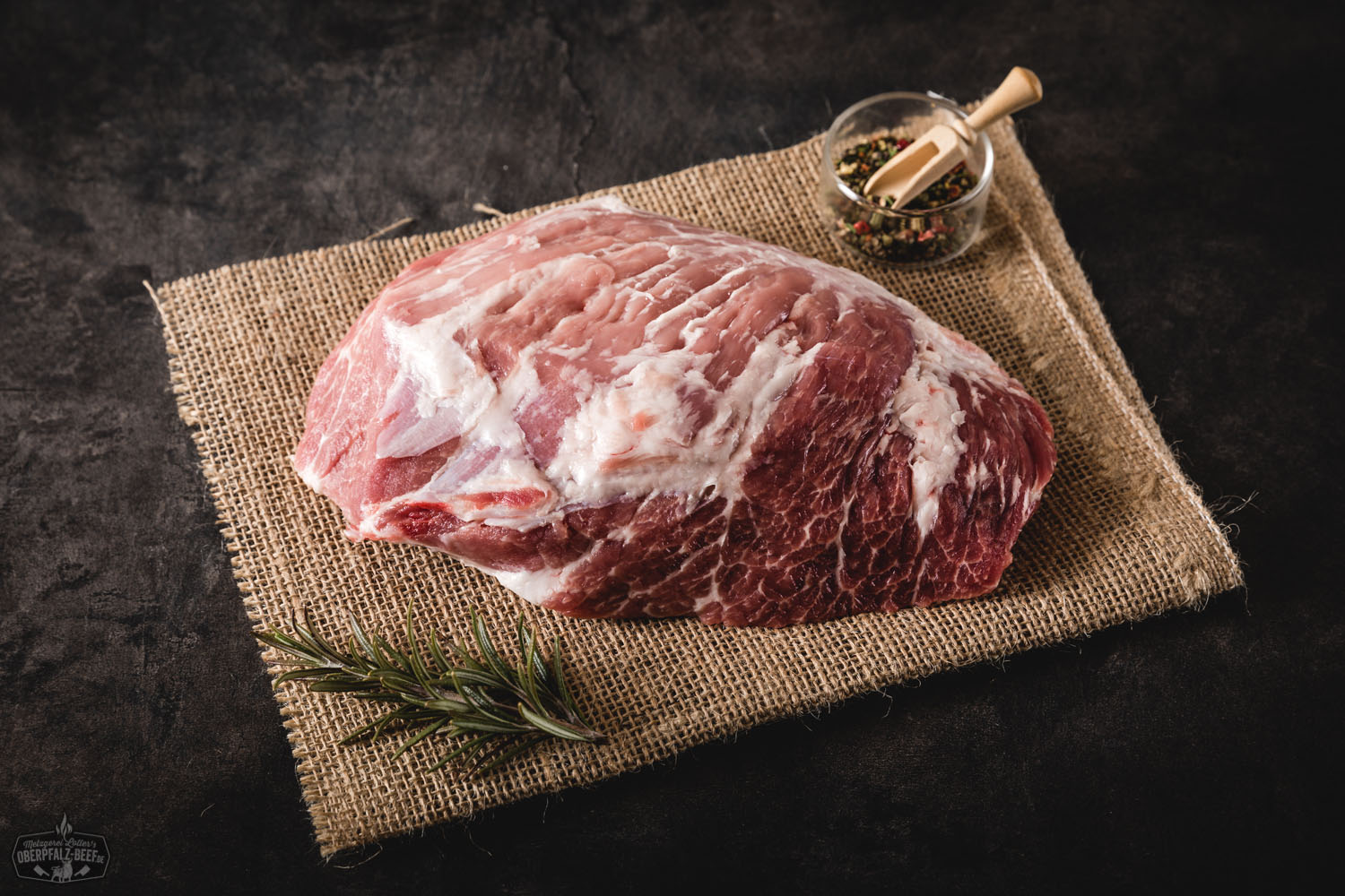 Rohes Presa-Steak vom Oberpfälzer Landschwein auf dunklem Untergrund, mit feiner Marmorierung und Sicht auf die Fleischstruktur – hochwertiges Schweinefleisch aus regionaler Zucht.