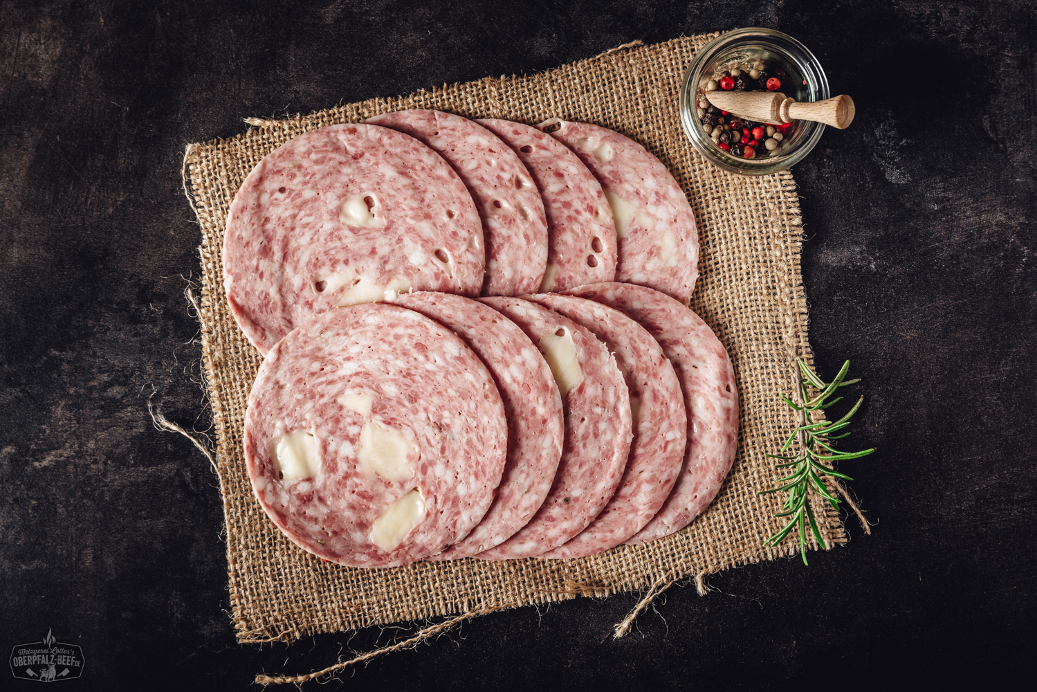 Geschnittene Käsebierwurst auf Holzbrett – herzhafte Wurst mit Käseanteil Käsebierwurst geschnitten - Delikatesse aus der Oberpfalz mit Bier- und Käsearomen, perfekt für Brotzeiten und Buffets. Frische, regionale Zutaten sorgen für einzigartigen Geschmack.