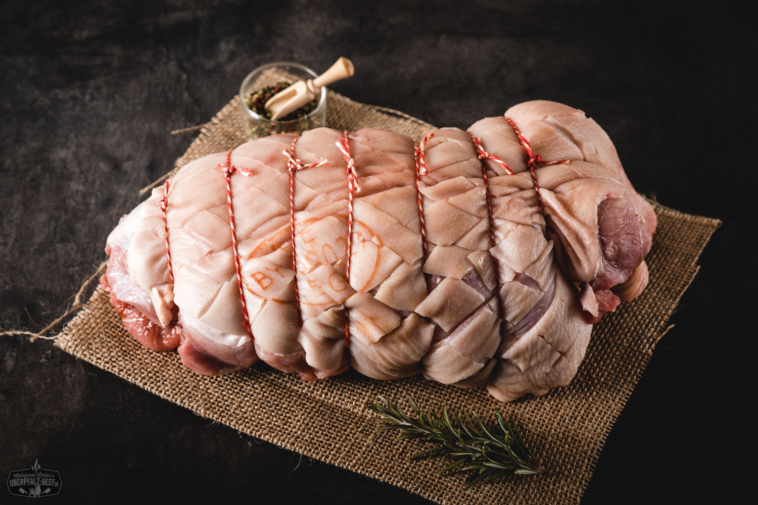Spanferkelschulter gerollt vom Oberpfälzer Landschwein – regionales Premiumfleisch online kaufen Gerollte Spanferkelschulter vom Oberpfälzer Landschwein, roh und sorgfältig gebunden, auf hellem Untergrund präsentiert – hochwertiges Schweinefleisch, ideal zum Braten oder Grillen.