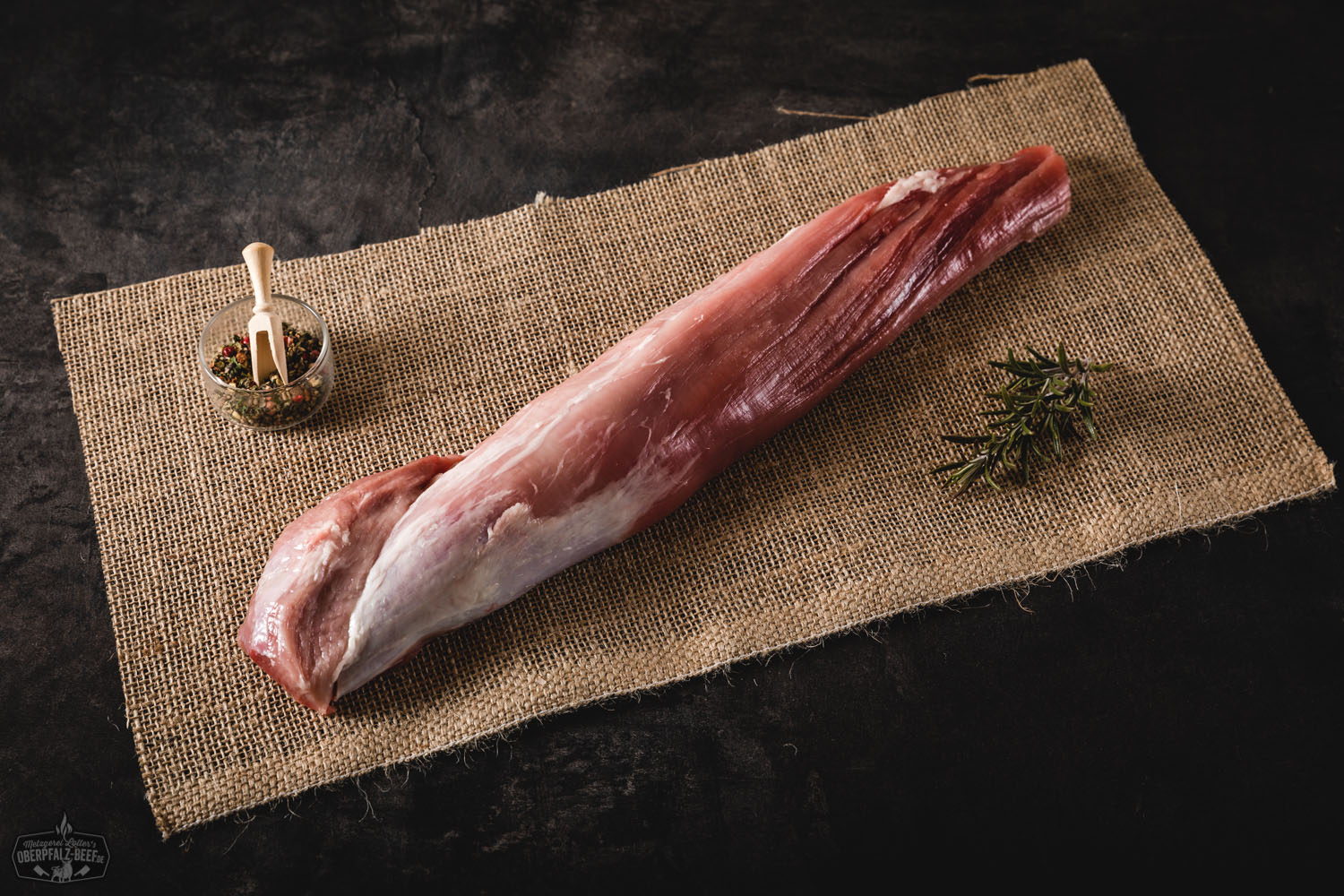 Filet oder Lende vom Oberpfälzer Landschwein – Frisches Schweinefleisch in Premiumqualität Rohes Filet vom Oberpfälzer Landschwein auf hellem Untergrund arrangiert, zart rosa mit feiner Marmorierung, garniert mit frischem Rosmarin und schwarzem Pfeffer – hochwertige Schweinelende für Fleischliebhaber und regionale Feinschmeckerküche.