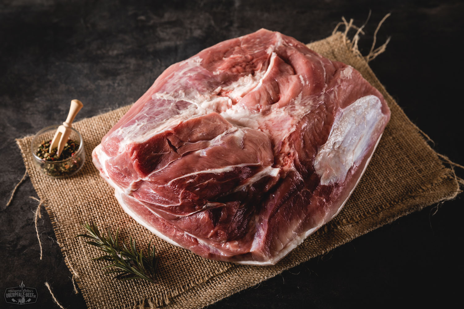 Krustenbraten vom Oberpfälzer Landschwein – knusprige Kruste, saftig gebratenes Fleisch aus der Keule, serviert auf Holzbrett mit frischen Kräutern und Sauce – traditionelle bayerische Spezialität, aufmerksam angerichtet für Food-Fotografie.