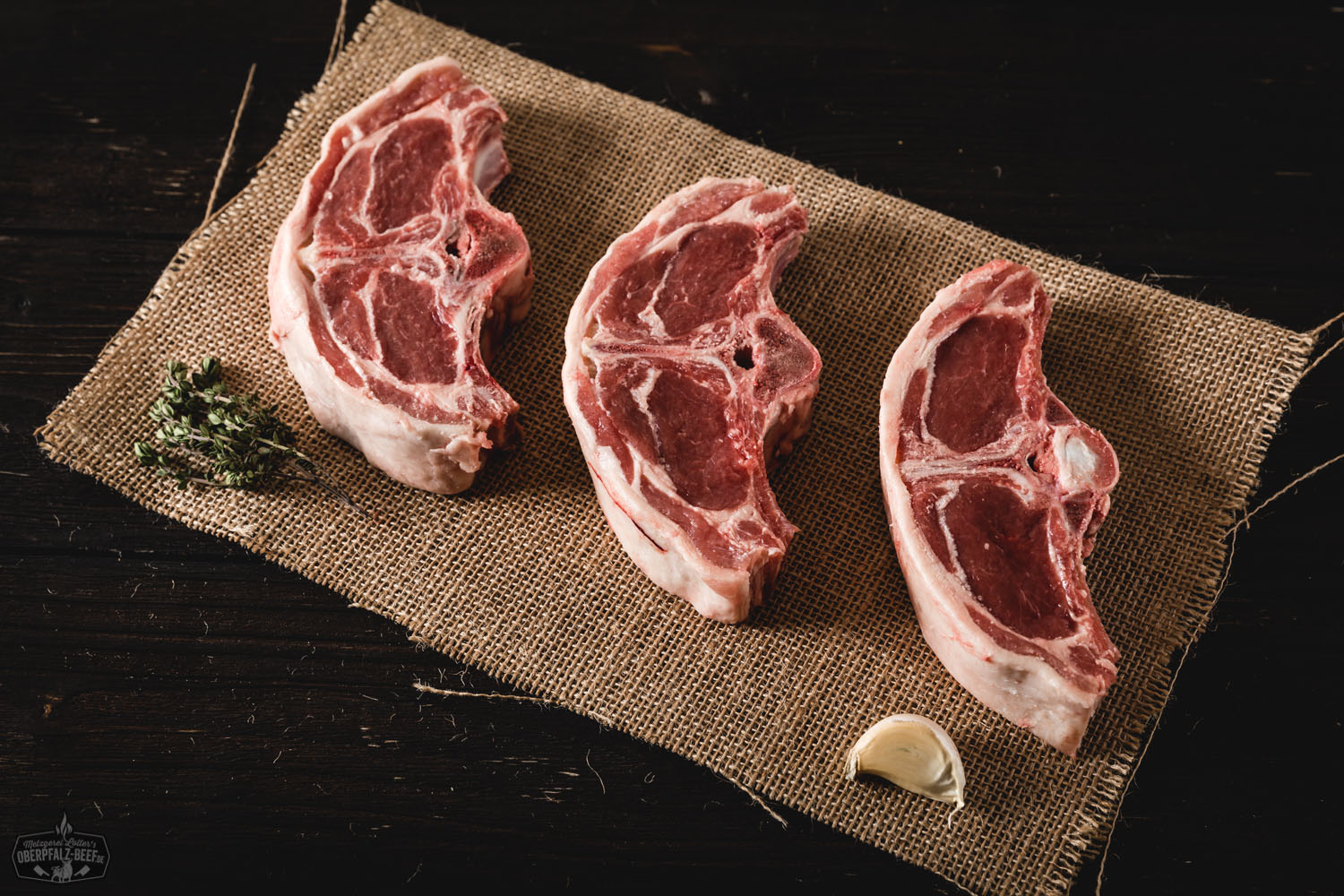 Lammkoteletts vom Rücken – Frische Chops für Grill und Pfanne Saftige, rosa gebratene Lammkoteletts mit kräftiger Kruste auf rustikalem Holzbrett angerichtet, garniert mit frischen Kräutern – hochwertiges Lammfleisch aus dem Rücken, ideal für Grill oder Pfanne.