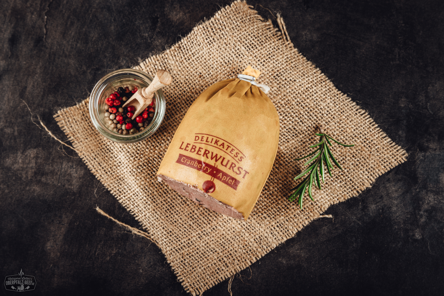 Kalbfleischleberwurst mit Cranberry und Apfel – Feine Delikatesse im Glas Glas mit Trüffel-Kalbsleberwurst auf dunklem Untergrund, daneben frische Trüffelscheiben und Gewürze dekorativ angerichtet – Gourmet-Delikatesse aus der Oberpfalz.