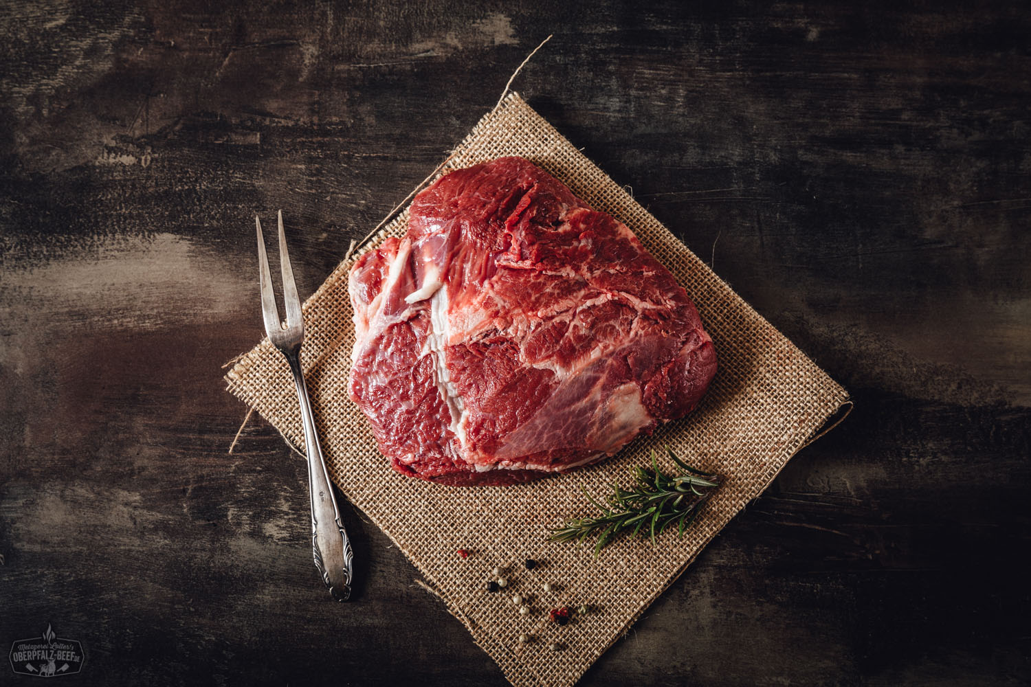 Zart geschmorte Ochsenbäckchen in dunkler Soße auf einem Bett aus cremigem Kartoffelpüree, angerichtet mit glasierten Karotten und frischen Kräutern auf einem weißen Porzellanteller.