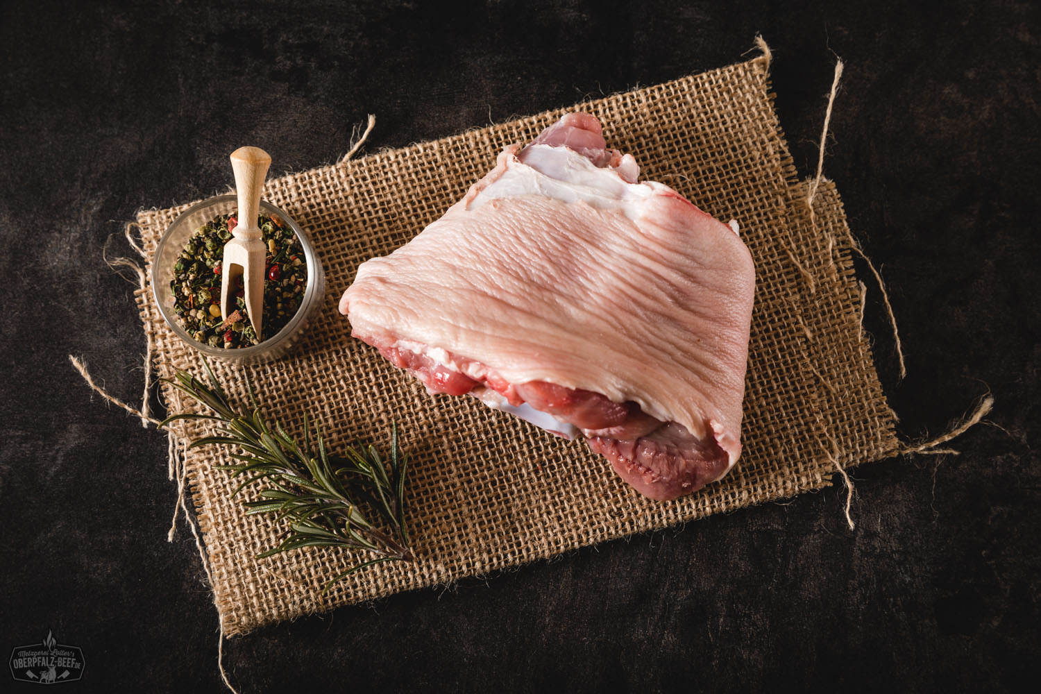 Spanferkel-Vorderhaxen vom Oberpfälzer Landschwein – zartes Fleisch regionaler Herkunft Gegarter Spanferkel-Vorderhaxe vom Oberpfälzer Landschwein auf Holzbrett, knusprige Kruste, saftiges Fleisch sichtbar, serviert mit Petersilie, rustikales Setting – hochwertige Spezialität aus regionaler Herstellung.