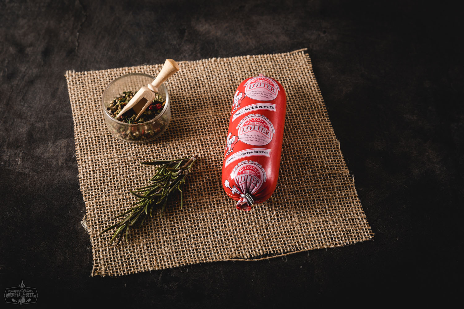 Ein Bild von einer groben Schinkenwurst im Mini-Format auf der Plattform Oberpfalz Beef, präsentiert auf einem hellen Hintergrund, die Wurst zeigt eine rustikale Textur und ist typisch für bayerische Fleischspezialitäten.