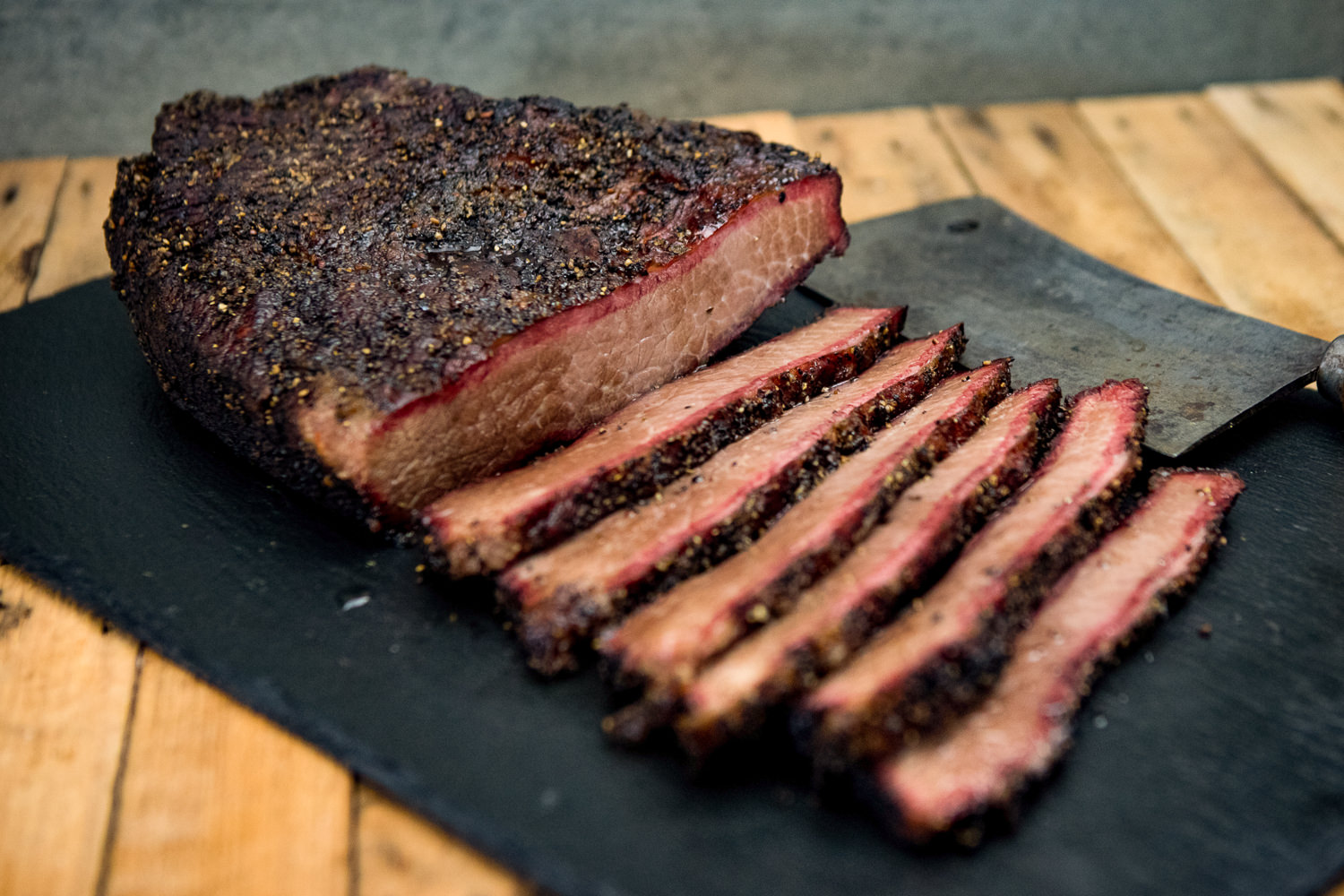 Beef Brisket Wet Aged vom Oberpfalz-Rind – zart gereiftes Rinderbruststück aus Bayern Nahaufnahme eines saftig gegarten Beef Briskets vom Oberpfalz-Rind auf Holzbrett, mit deutlich sichtbarer feiner Marmorierung, zart rosa Fleischkern und knuspriger Kruste – perfekt geeignet für BBQ, Grill oder Smoker.