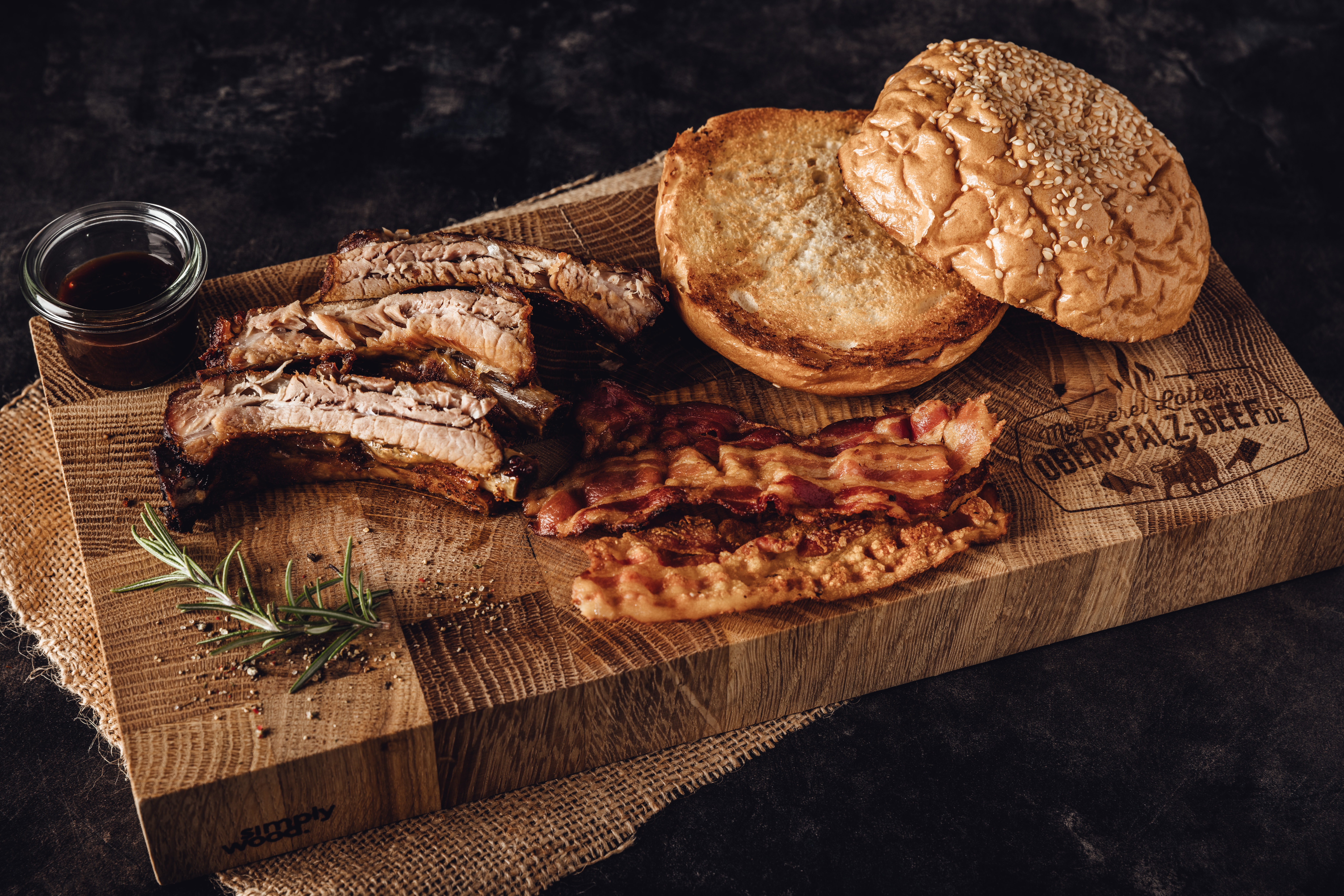 "Zart gegarte Baby Back Ribs Box - Perfekt zum Genießen" Zarte und saftige Baby Back Ribs in einer Box, bereit zum Verzehr, präsentiert auf einem Holztisch mit Gewürzen und Soßen, ideal für BBQ-Liebhaber und Grill-Enthusiasten.