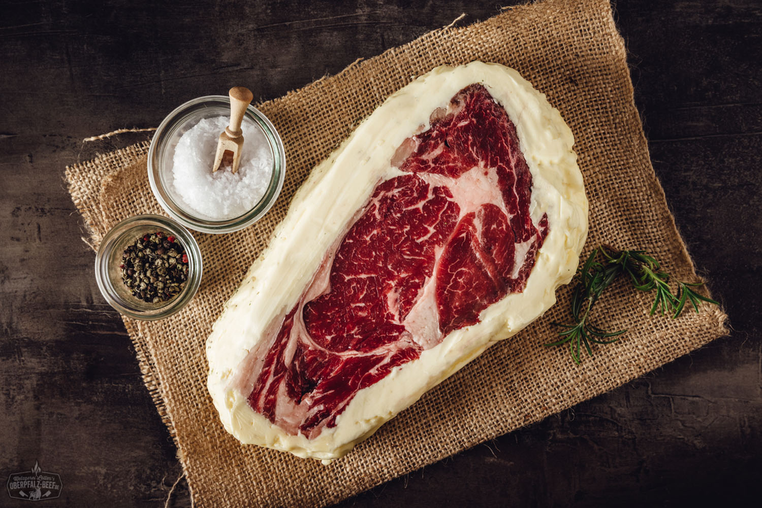 Butter Aged Entrecôte (Rib-Eye Steak) vom Oberpfalz-Rind – Premium Qualität aus Bayern Rohes Entrecôte-Rib-Eye-Steak vom Oberpfalz-Rind auf dunklem Untergrund, marmoriertes, saftiges Rindfleisch in hochwertiger Butter-Aged-Qualität, ideale Struktur und Fettverteilung für Premium-Steakgenuss.