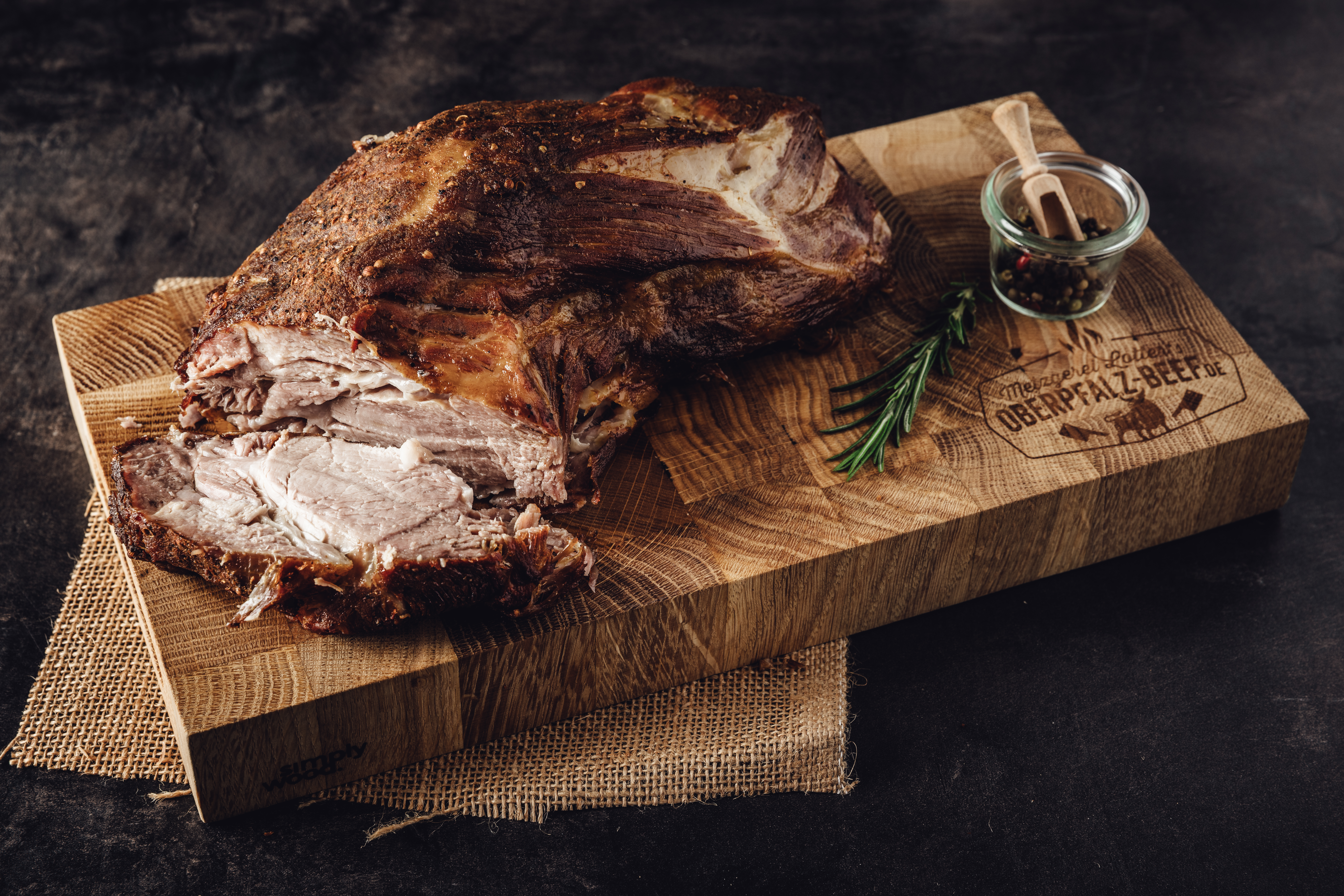 Schweinebraten Hals Rezept mit Knuspriger Kruste und Saftigem Fleisch Leckeres Schweinebraten-Halsstück auf einem rustikalen Holzbrett, umgeben von Gewürzen und Kräutern, perfekt gegart und serviert als Oberpfalz Beef Spezialität.