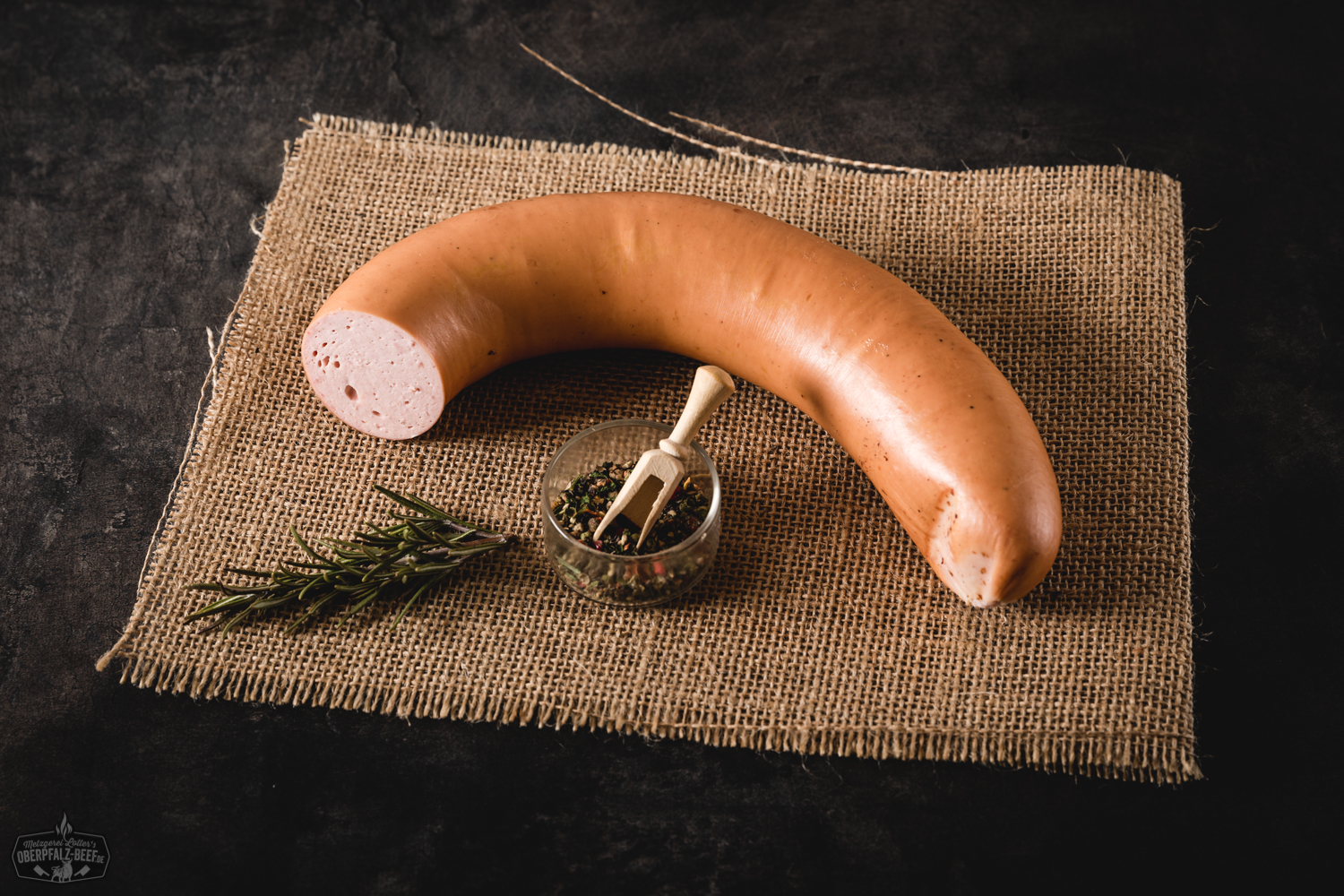 Wurstsalatwurst am Stück auf einem Schneidebrett aus Holz, perfekt für die Zubereitung von herzhaftem Wurstsalat, nahe Ansicht, ideal für traditionelle bayrische Küche