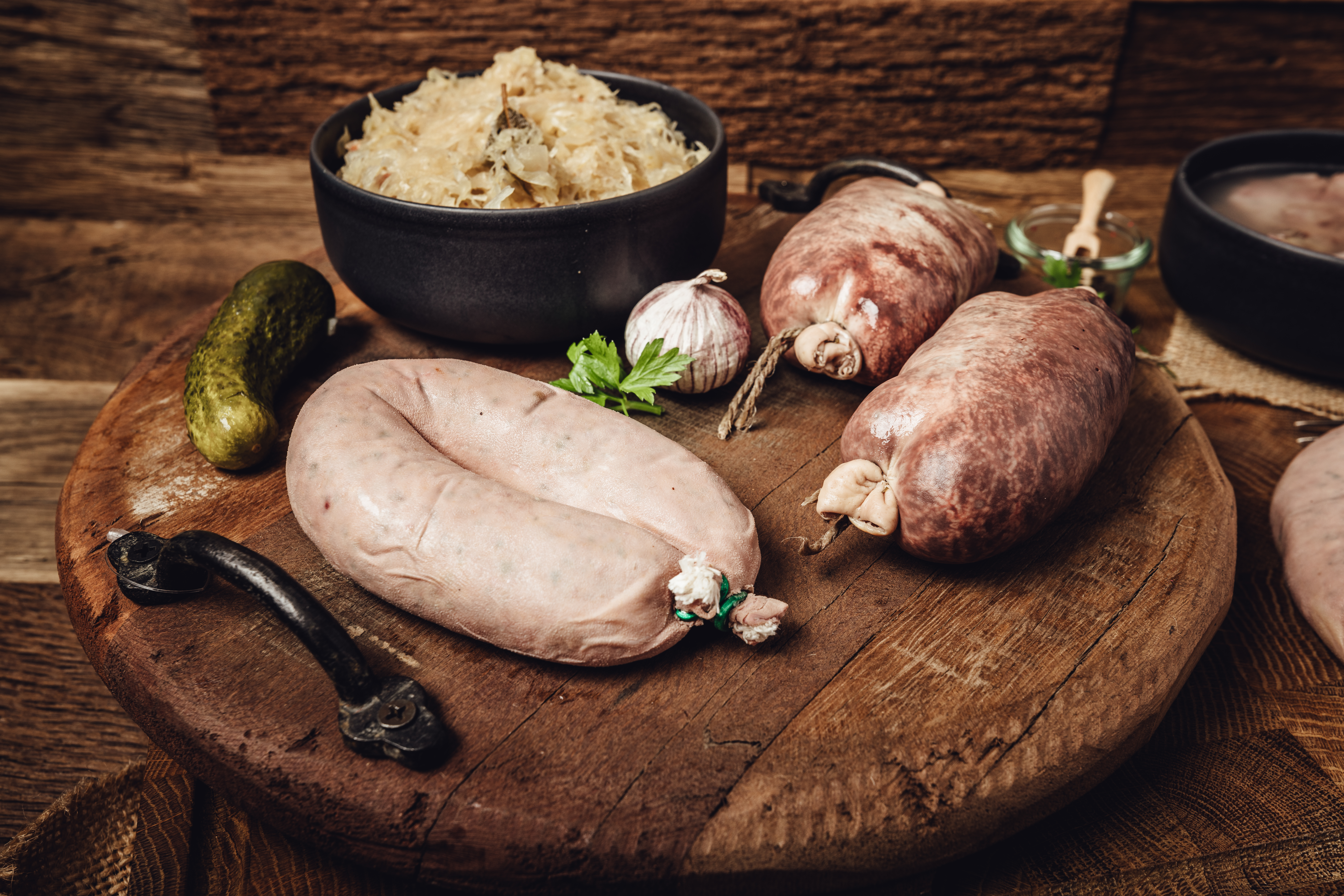 Frische Leberwurst im Naturdarm auf Holzbrett mit Kräutergarnitur Frisch aufgeschnittene Blutwurst mit sichtbaren Einlagen aus Speck, angerichtet auf einem dunklen Holzbrett vor rustikalem Hintergrund – traditionelle bayerische Wurstspezialität.