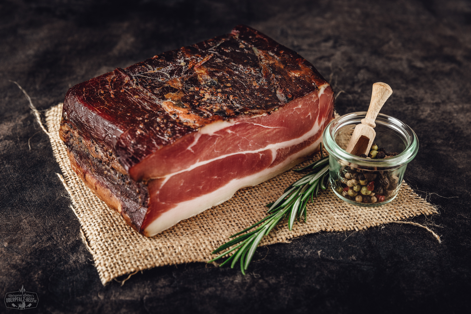 Oberpfälzer Bauernschinken aus der Hüfte – am Stück geräuchert und naturgereift Oberpfälzer Bauernschinken aus der Hüfte am Stück auf einem Holztisch präsentiert, ideal für Liebhaber traditioneller bayerischer Fleischspezialitäten.