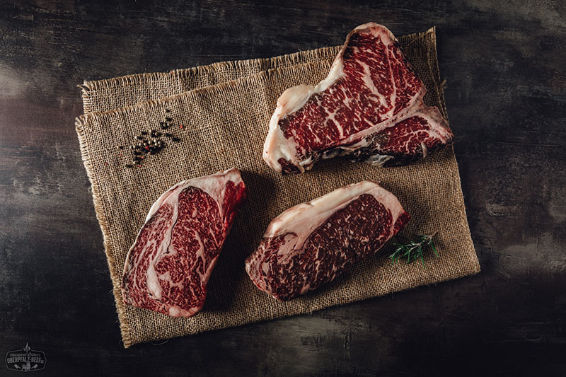 Traditionelles Herrengedeck mit Bier und Schnaps auf Holzbrett – Oberpfalz Beef Ein elegantes Herrengedeck mit einem saftigen Oberpfalz Beef Steak, einem Glas Rotwein und stilvollem Besteck in rustikalem Ambiente. Perfekt für Genießer und Liebhaber hochwertiger Fleischgerichte.
