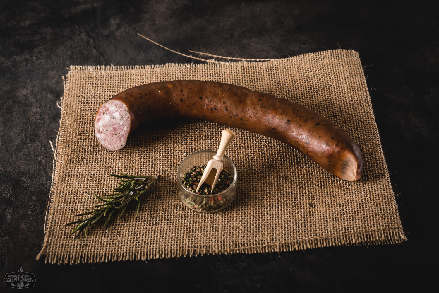 Hausgemachte Stadtwurst in Scheiben auf einem Holzbrett angerichtet, dekoriert mit frischen Zwiebelringen und Petersilie, daneben ein Brotkorb und Senf – traditionelle bayerische Brotzeit mit regionaler Wurst aus der Oberpfalz.