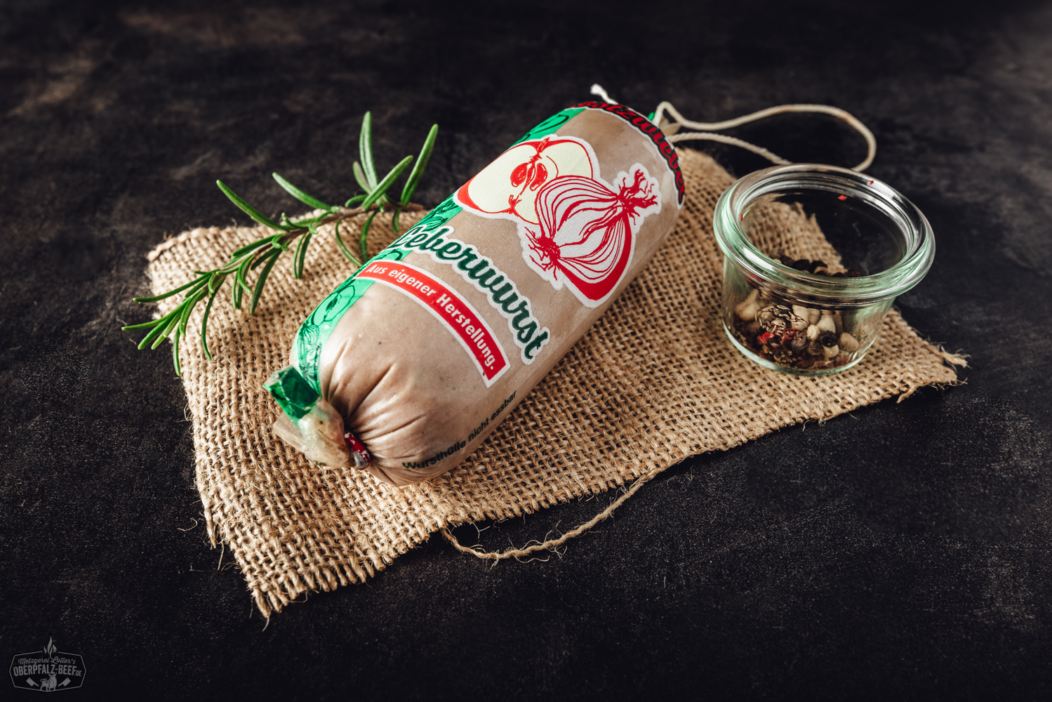 Apfel-Zwiebel-Kalbsleberwurst als Portion – Hausmacher Wurst im Naturdarm Gegrillter Kräuterkäse auf schwarzem Untergrund, rechteckiger Käse mit goldbrauner Kruste, bestreut mit grünen Kräutern, serviert auf Brett mit Beilagen wie Rosmarinzweig und Gewürzen – deftiger vegetarischer Grillgenuss aus der Oberpfalz.
