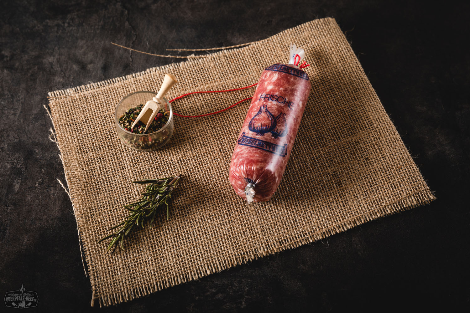 Zwiebelmettwurst als Portionswurst – herzhafte Spezialität aus der Oberpfalz Zwiebelmettwurst in Portionsgröße: Zwei vakuumverpackte Würste mit grobkörniger, rotbrauner Mettfüllung und sichtbaren Zwiebelstückchen, nebeneinander auf weißem Hintergrund, typisch bayerische Delikatesse der Oberpfalz.