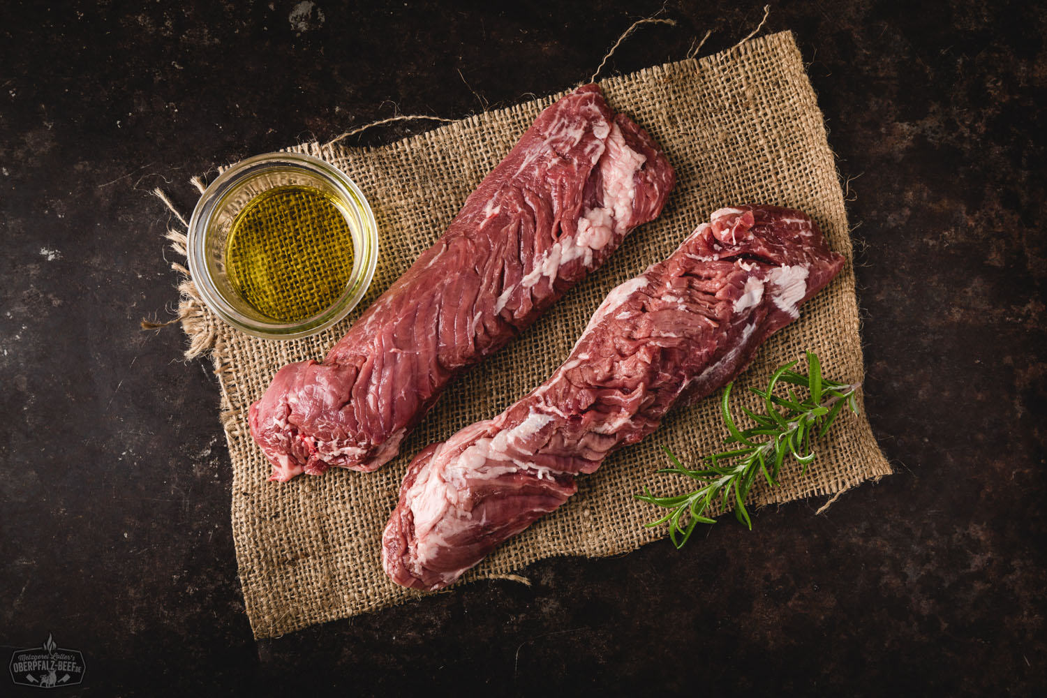 Hanging Tender (Onglet) vom Oberpfälzer Milchkalb – zartes Kalbfleisch in Premiumqualität Rohes Hanging Tender (Onglet) vom Oberpfälzer Milchkalb auf dunkler Unterlage, fein marmoriert mit sichtbarer Fleischstruktur, daneben frische Kräuter, grobes Salz und bunte Pfefferkörner–hochwertiges Kalbfleisch für Steak oder Grillgerichte.