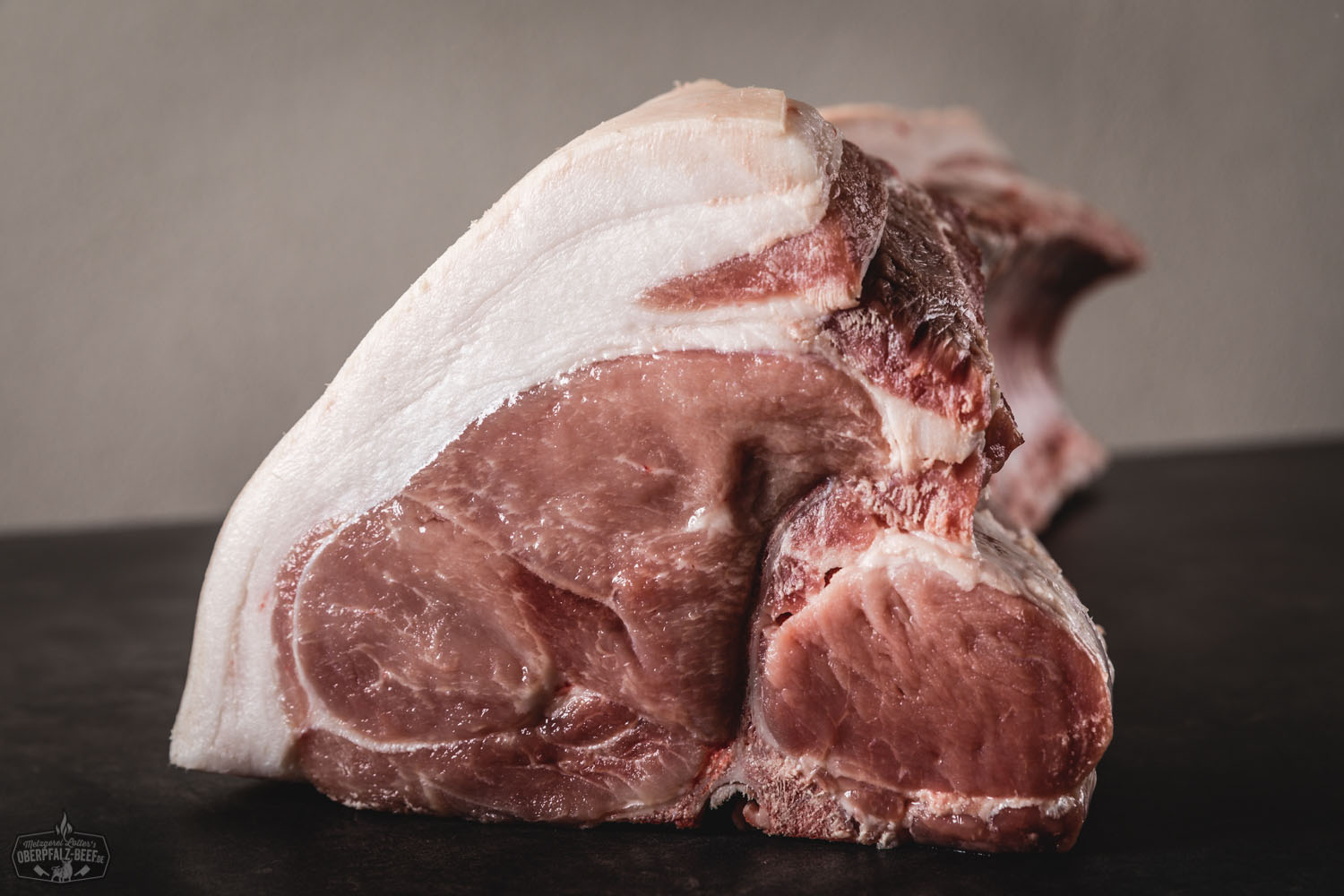 Frisches halbes Kotelett Filetcut vom Oberpfälzer Landschwein – regionales Schweinefleisch in Premiumqualität Frisches halbes Kotelett vom Oberpfälzer Landschwein im Filetcut, roh und saftig mit zarter Marmorierung auf dunklem Untergrund, ideal für Grill oder Pfanne.