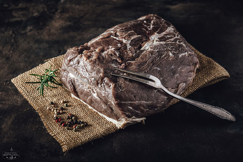 Eingelegter Sauerbraten mit Zwiebeln und Gewürzen – Traditionelles deutsches Rindfleischgericht Nahaufnahme eines rohen, eingelegten Sauerbraten-Stücks mit sichtbaren Pfefferkörnern, Zwiebelringen und Lorbeerblättern in einer dunklen Marinade – traditionelles deutsches Schmorgericht, perfekt vorbereitet zum Kochen.