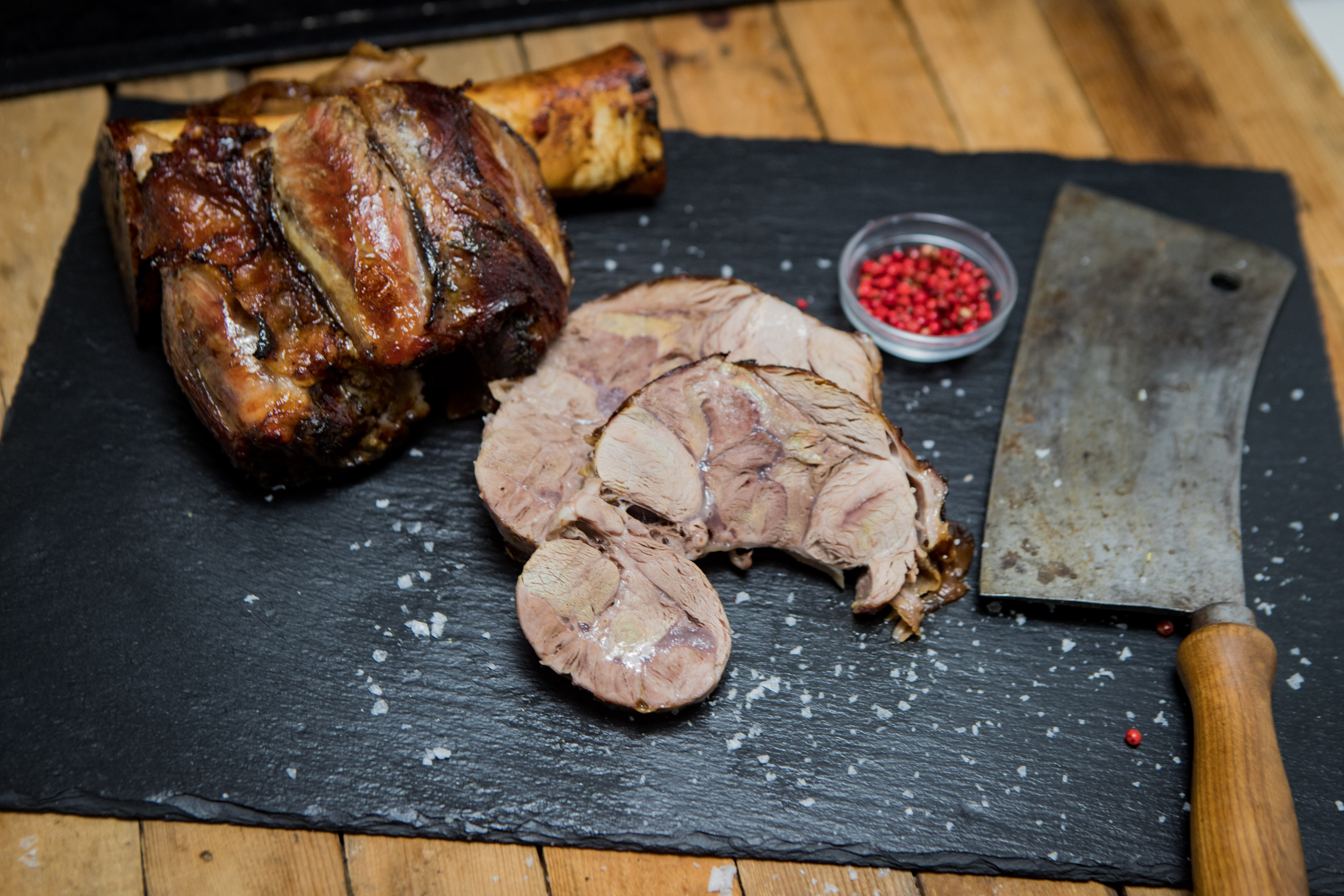 Hintere Haxe vom Oberpfälzer Milchkalb – zartes Kalbfleisch regionaler Herkunft Rohe hintere Kalbshaxe vom Oberpfälzer Milchkalb auf dunklem Untergrund, umgeben von frischen Kräutern, grobem Salz und Pfefferkörnern – hochwertiges Kalbfleisch für Schmorgerichte und traditionelle Rezepte.