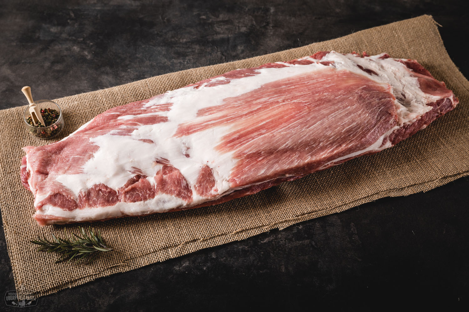 St. Louis Style Ribs vom Oberpfälzer Landschwein – saftig gegrillt und perfekt mariniert Gegrillte, fleischige St. Louis Style Ribs vom Oberpfälzer Landschwein, saftig glasiert mit dunkler BBQ-Sauce, knusprig karamellisiert, serviert auf dunklem Holzbrett mit leichtem Rauch im Hintergrund – rustikal angerichtet für authentischen BBQ-Genuss.