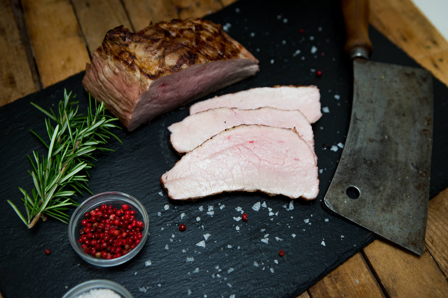 Tafelspitz vom Oberpfälzer Milchkalb – zartes Kalbfleisch in Premiumqualität Rosa gebratener Tafelspitz vom Oberpfälzer Milchkalb, saftig aufgeschnitten und auf einem dunklen Holzbrett angerichtet, garniert mit Rosmarinzweig, Meersalz und buntem Pfeffer – hochwertiges Kalbfleisch in Premium-Qualität für Feinschmecker.