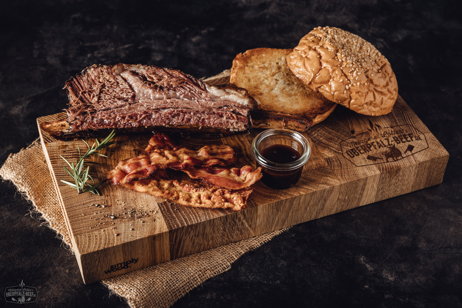 Sous Vide Beef Short Ribs vom Oberpfalz-Rind – zart gegarte Premium-Rippchen in Box Zart gegarte Beef Short Ribs vom Oberpfalz-Rind in rustikaler Holzbox angerichtet, mit dunkler Kruste und saftigem Fleisch, daneben frische Rosmarinzweige und grobes Salz als Garnitur – hochwertiges Sous-vide Beef für BBQ-Liebhaber.