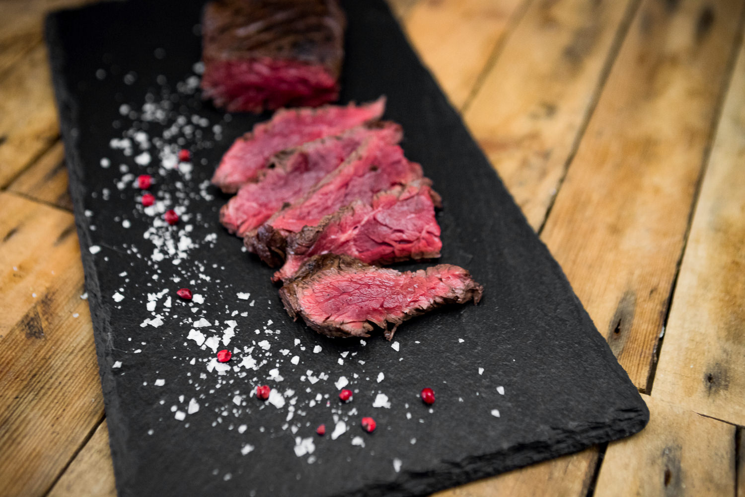 Hanging Tender (Onglet) vom Oberpfälzer Milchkalb – Zartes Kalbfleisch in Premiumqualität Rohes Hanging Tender (Onglet) vom Oberpfälzer Milchkalb auf dunklem Untergrund, saftig marmoriert, mit frischen Rosmarinzweigen und zerstoßenem Pfeffer garniert – hochwertiges Kalbfleisch für Steak-Liebhaber.