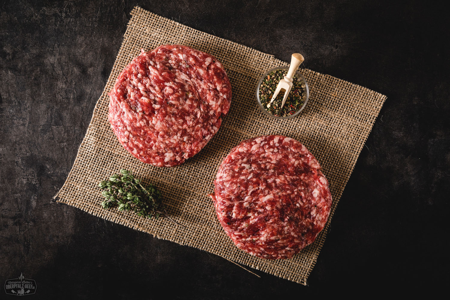 Wildburger mit Rindfleisch-Patty, Preiselbeeren und Rucola im rustikalen Bun Wildburger mit gegrilltem Wildfleisch-Patty, frischem Salat, roten Zwiebeln, geschmolzenem Käse und knusprigem Burger-Brötchen, serviert auf einem Holzbrett – rustikale Präsentation mit Fokus auf hochwertiges Wildfleisch aus der Oberpfalz.