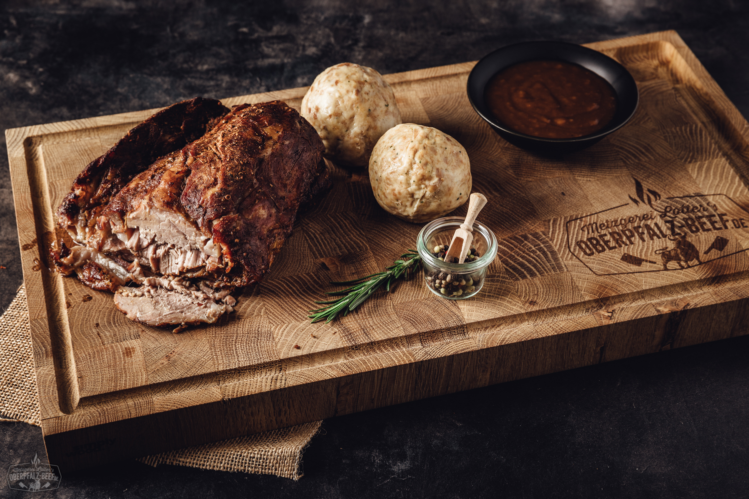 Sous-vide gegarter Kalbsbraten aus der Keule in Premium-Box Knusprig gebratener Schweinekrustenbraten vom Bauch, in gleichmäßige Scheiben geschnitten, mit goldbrauner, knuspriger Kruste, saftigem Fleisch und zartem Fettrand, serviert auf dunklem Holzbrett – appetitliches Sous-vide-Gericht für Fleischliebhaber.