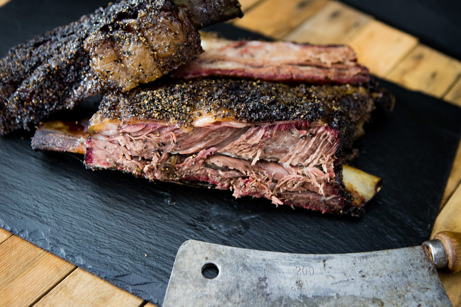 Dry Aged Short Ribs vom Oberpfalz-Rind – Premium Rindfleisch in Portionen Portionsstück Short Ribs dry aged vom Oberpfalz-Rind, roh auf dunkler Oberfläche angerichtet; gut marmoriertes Rindfleisch mit sichtbarer Knochenstruktur, hochwertig und frisch, ideales BBQ-Fleisch für Grill oder Slow Cooking.