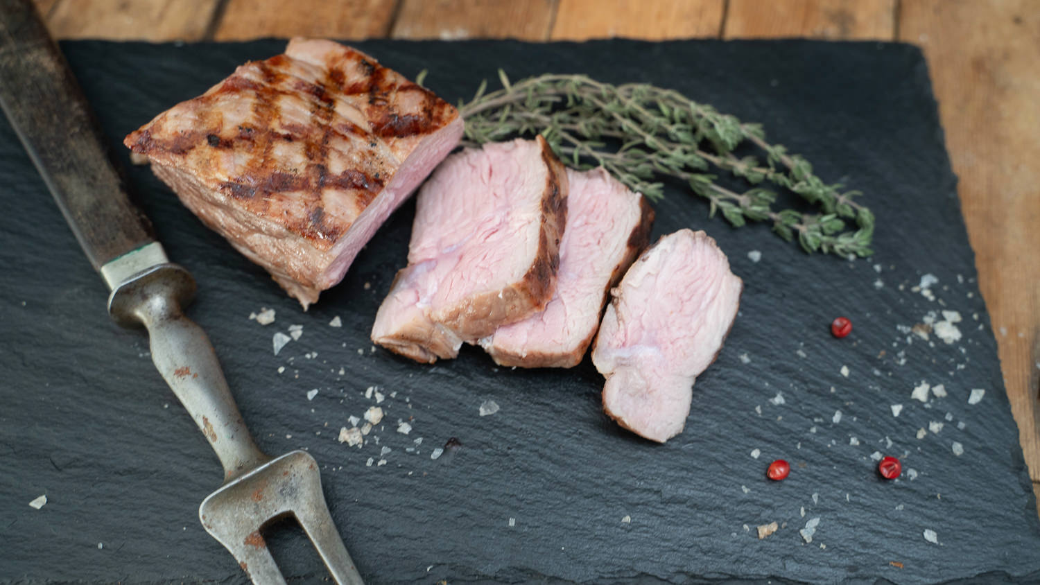 Zartes Kalbshüftsteak frisch gegrillt auf Holzbrett serviert Kalbs-Huftsteak roh auf dunklem Holzbrett angerichtet, mit grobem Meersalz bestreut, frischen Rosmarinzweigen und Knoblauch dekoriert – hochwertiges Fleisch, ideal zum Grillen oder Braten.