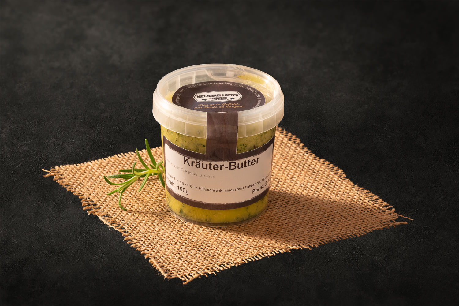 Eine dekorativ angerichtete Scheibe Kräuterbutter mit sichtbaren Kräutern liegt auf einem rustikalen Holzbrett, umgeben von frischen Kräutern wie Petersilie und Rosmarin – ideal als Beilage zu gegrilltem Fleisch oder Steak.