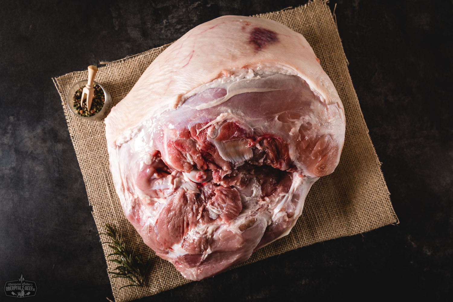 Spanferkelkeule vom Oberpfälzer Landschwein – goldbraun knusprig gebraten, saftig tranchiert und auf einem Holzbrett angerichtet, mit frischen Kräutern garniert; traditionelles bayerisches Fleischgericht in hochwertiger Qualität.