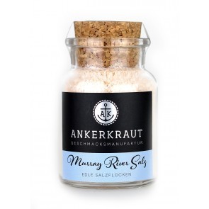 Glas mit grobem, rosafarbenem Murray River Salz auf dunkler Steinplatte, daneben Holzlöffel mit Salz und Verpackung mit Aufschrift „Murray River Salt“ – hochwertiges australisches Gourmetsalz in natürlicher Präsentation.