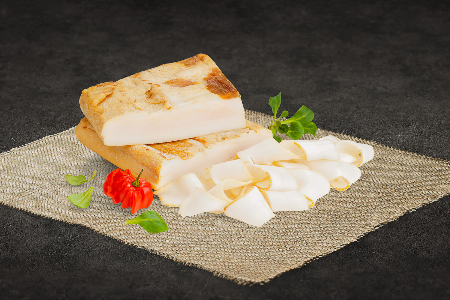 Aufgeschnittener Rinderbierschinken aus 100 % Rindfleisch, appetitlich angerichtet auf einem Holzbrett mit frischen Kräutern, ideal für Brotzeit oder kalte Platten.