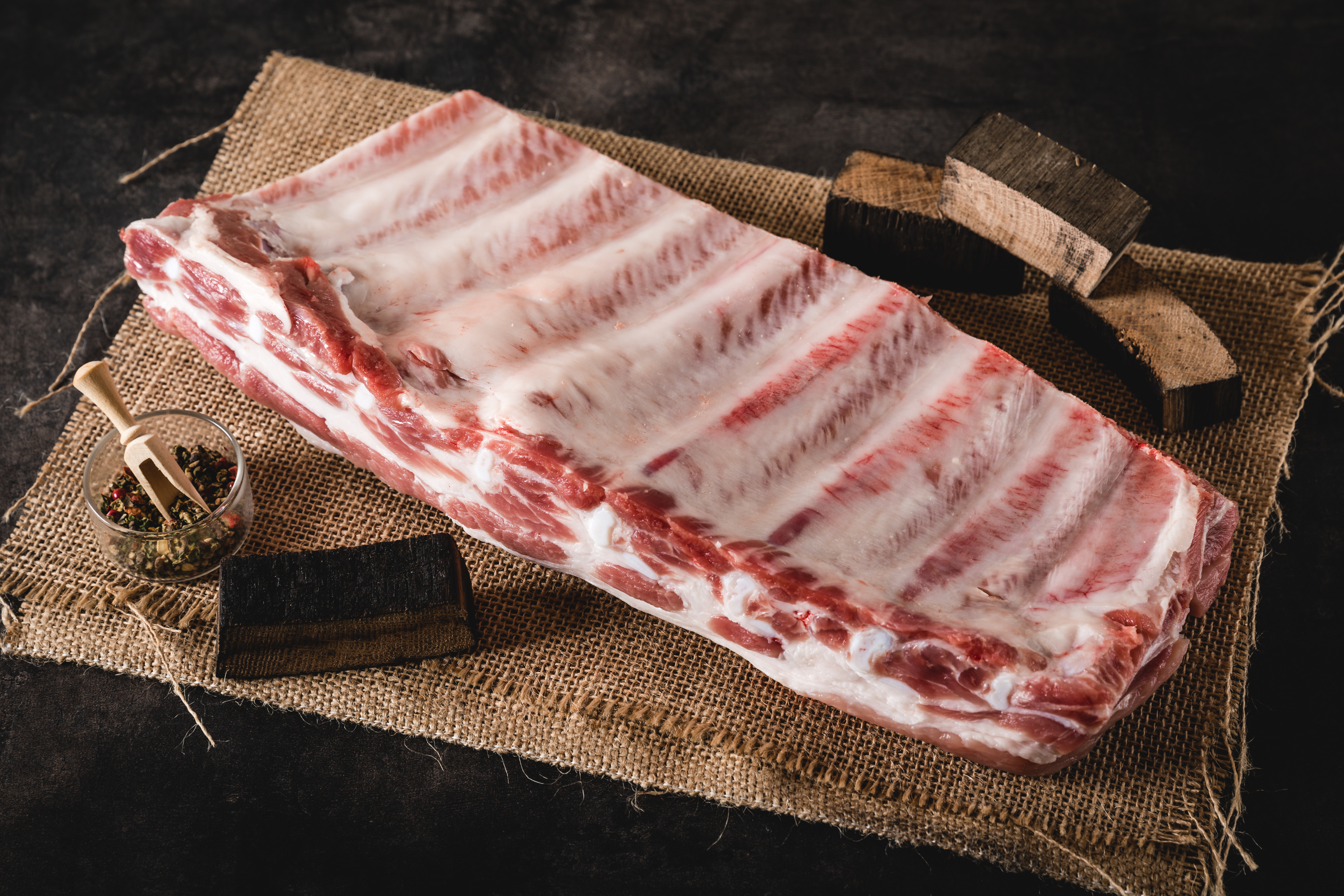 Schwein auf der Weide mit Oberpfalz Beef Qualitätssiegel Frische Schweinekarree-Steaks auf einem bearbeiteten Holzbrett, perfekt für den Grill oder das Braten in der Pfanne. Qualitativ hochwertiges Oberpfalz-Beef Fleisch.