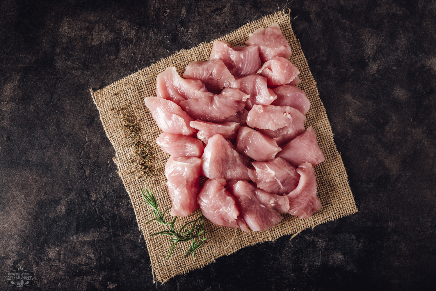 Handgeschnittenes Putenbrustfilet für Fondue – frisch und zart Nahaufnahme von zart rosa geschnittenem Putenbrust-Fleisch für Fondue, sorgfältig per Hand geschnitten und auf einem dunklen Teller angerichtet, mit dezentem Lichteinfall, ideal für ein festliches Essen oder gesellige Fleischfondue-Abende.